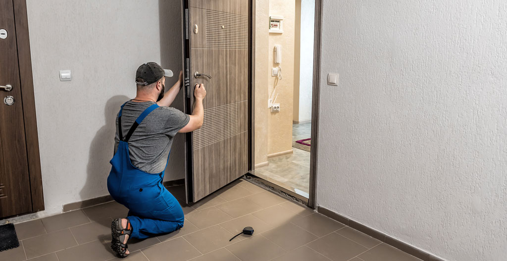 Artisan serrurier en intervention sur une porte blindée dans un appartement